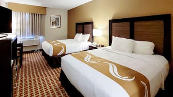 A hotel room with two beds, a desk, a chair, a TV, and a window with curtains.