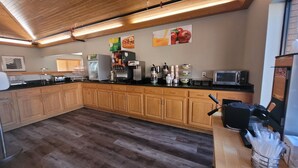 A kitchen with wooden cabinets, a microwave, a coffee machine, and various appliances. - Quality Inn & Suites Marion (Marion)