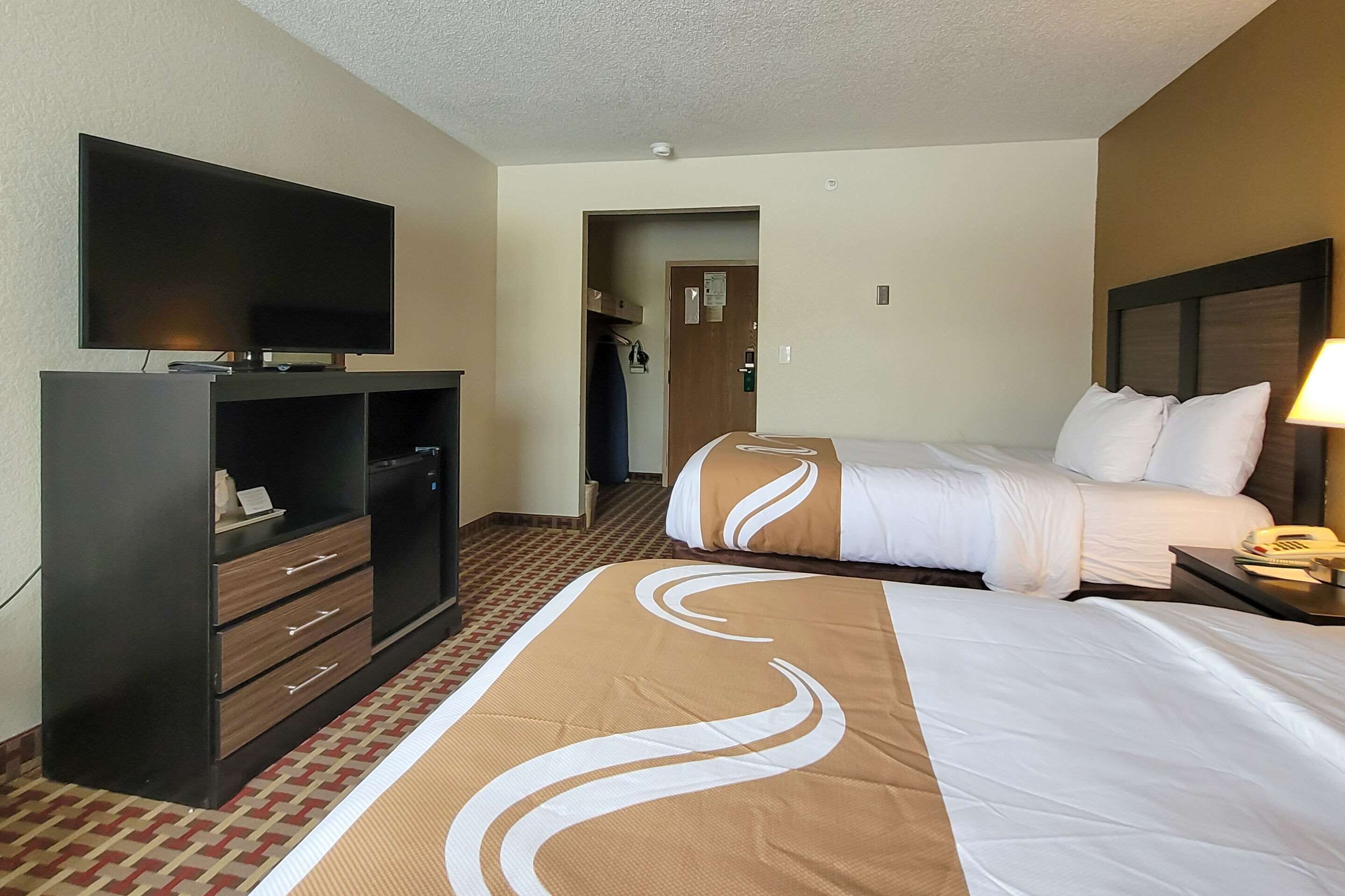 Una habitación de hotel con cama, televisión, escritorio y armario.