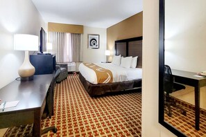 A hotel room with a bed, desk, chair, and a large mirror.
