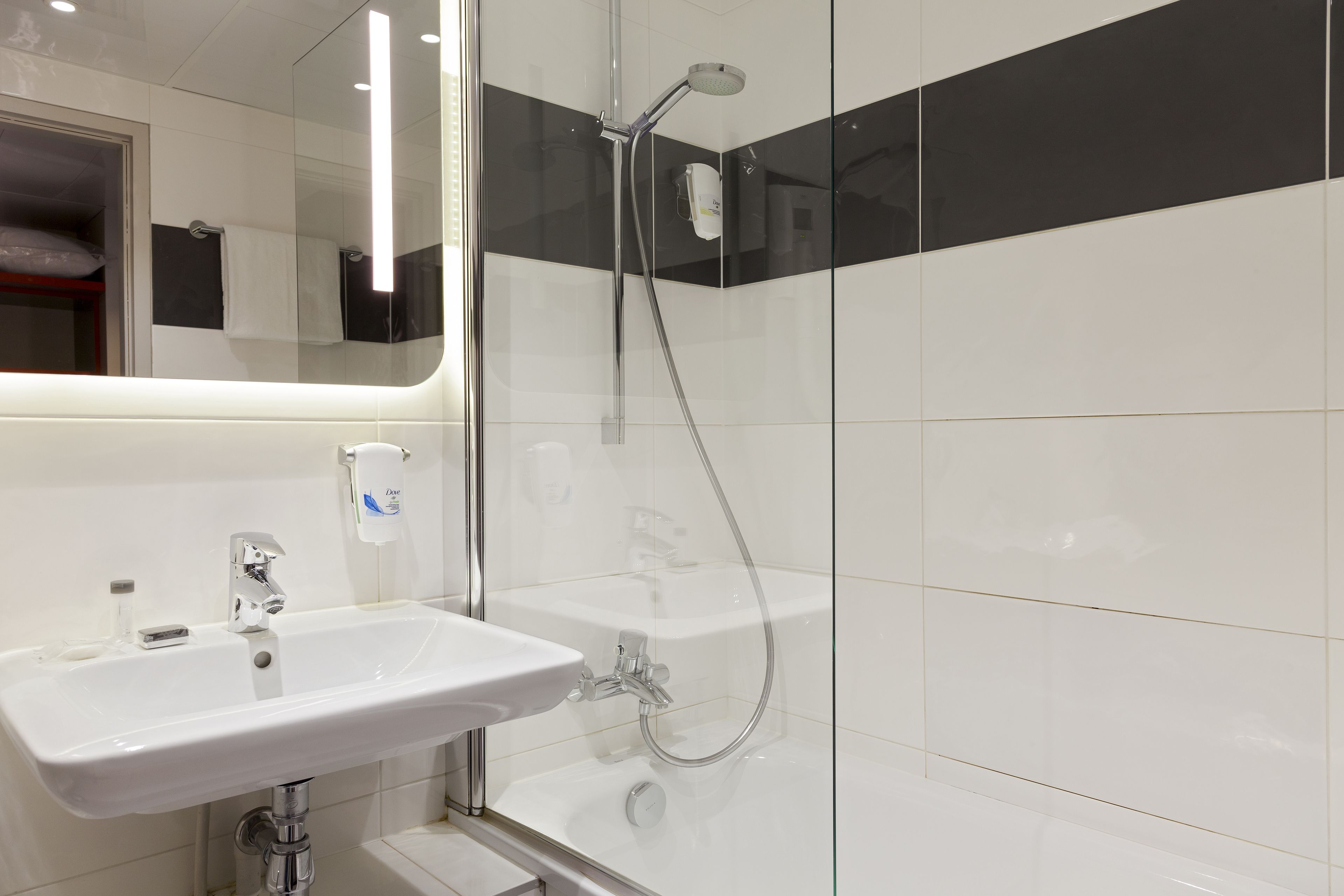A modern bathroom with a glass shower enclosure, a white sink, and a mirror.