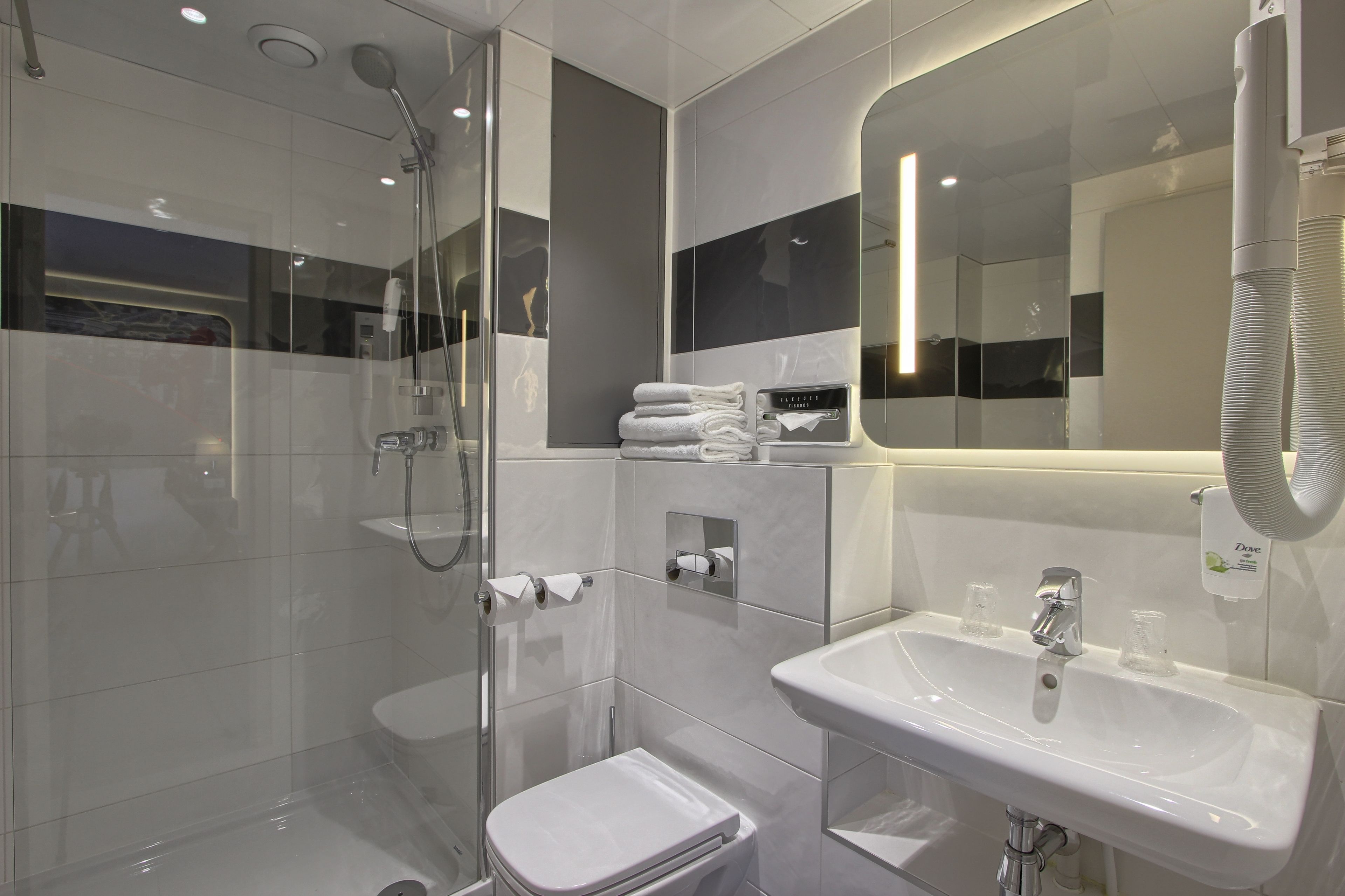 A modern bathroom with a glass-enclosed shower, a white sink, and a mirror.