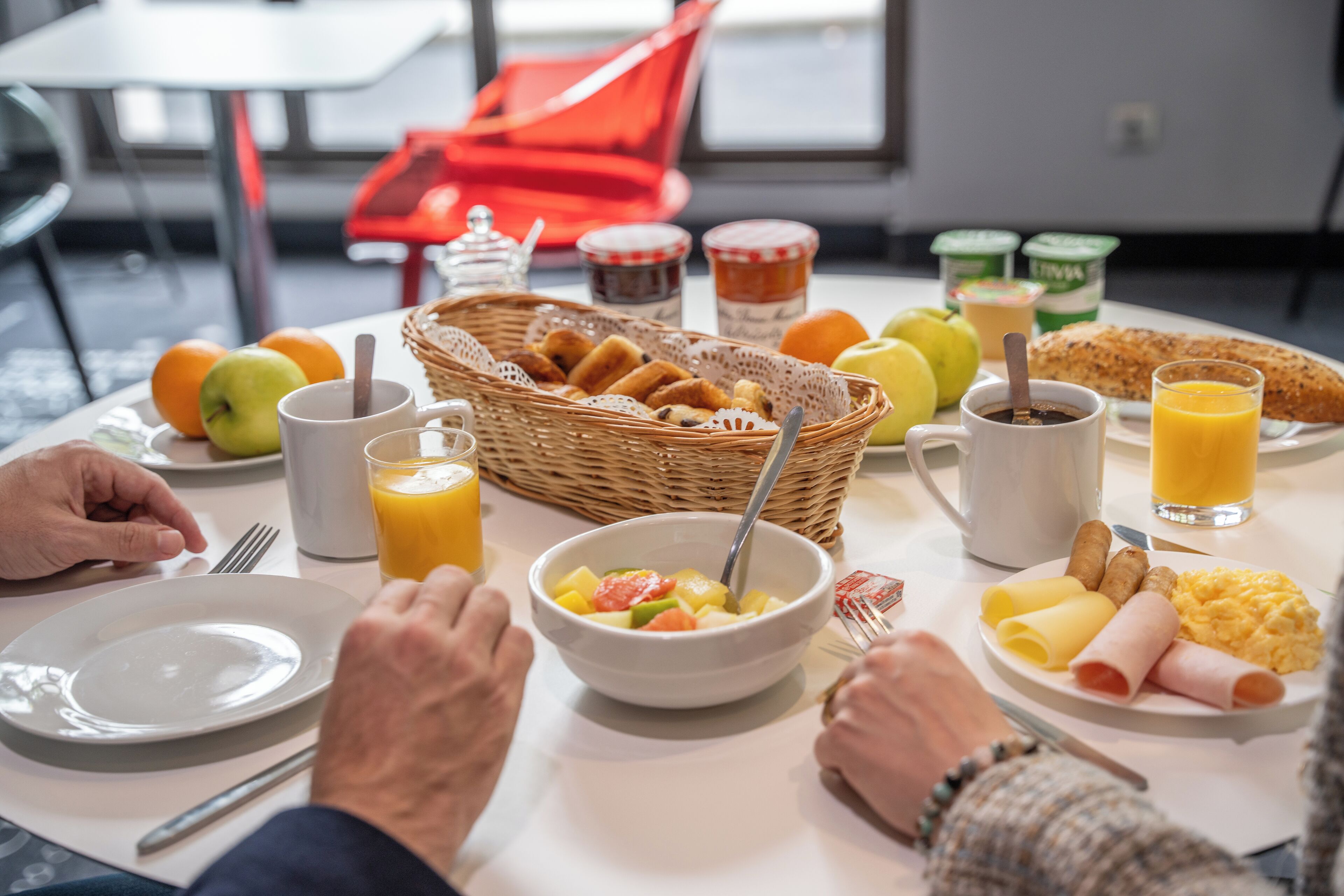A breakfast table with various food items, including fruits, bread, and beverages.