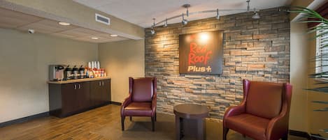 Un área de recepción con pared de piedra, dos sillones de cuero, una mesita y una barra con bebidas.