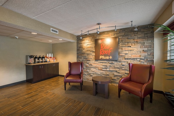 A reception area with a stone wall, two leather chairs, a small table, and a counter with beverages.