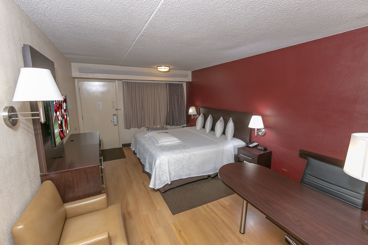 Een hotelkamer met een bed, nachtkastjes, een bureau, een stoel en een televisie.