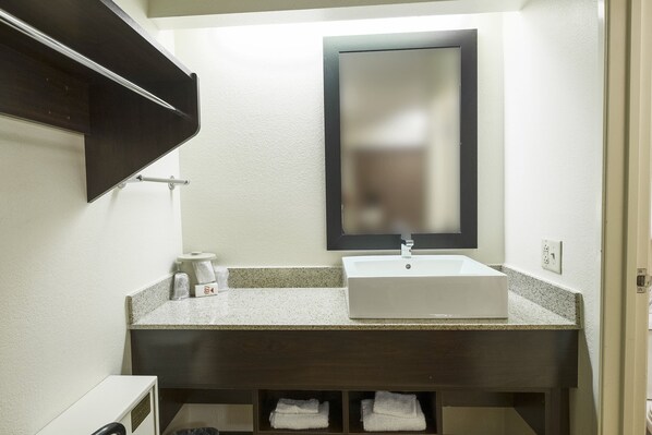 A bathroom with a white sink, dark countertop, and a mirror with a black frame. - Red Roof Inn PLUS+ West Springfield (West Springfield)
