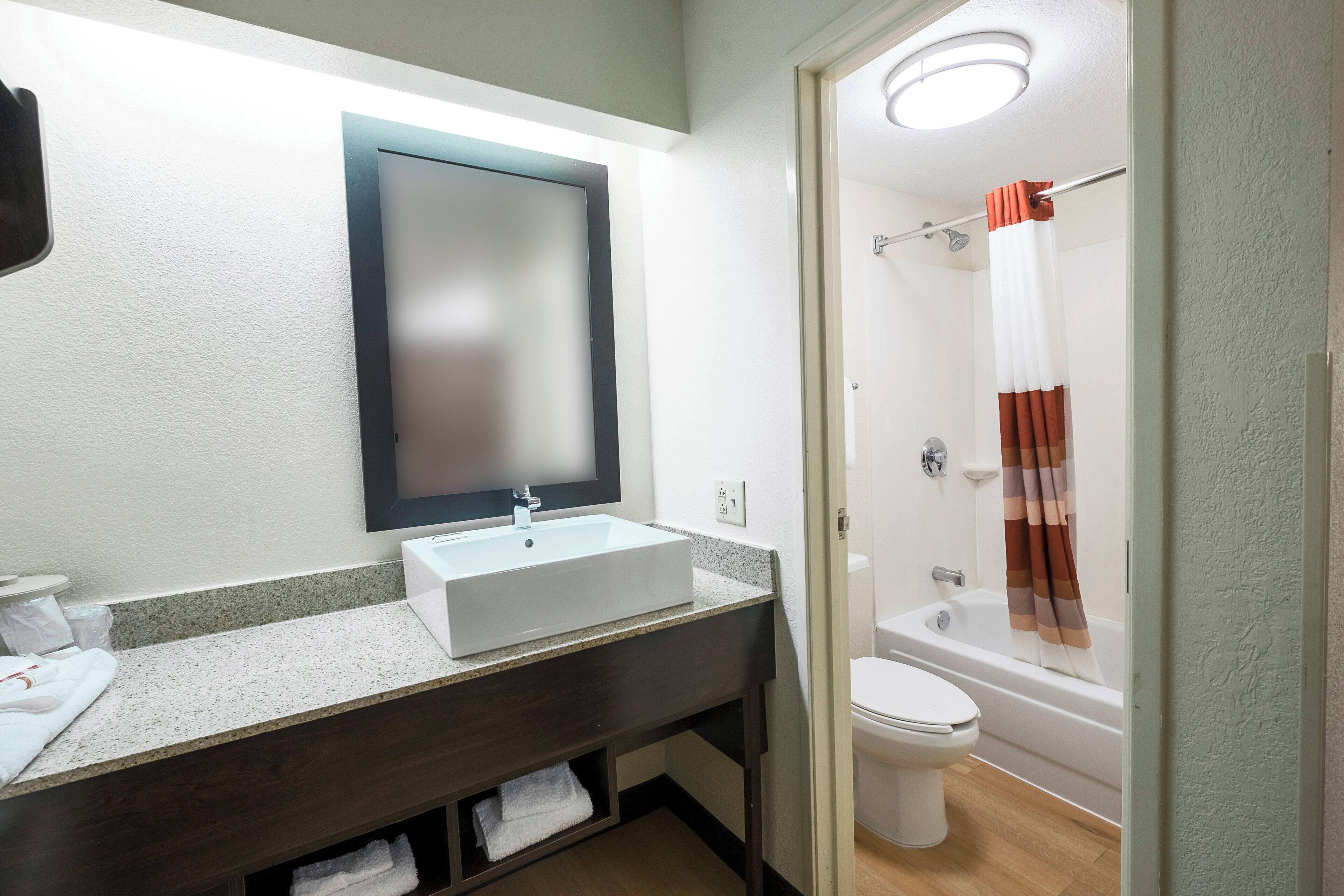 A bathroom with a white sink, a mirror, a toilet, and a shower area.