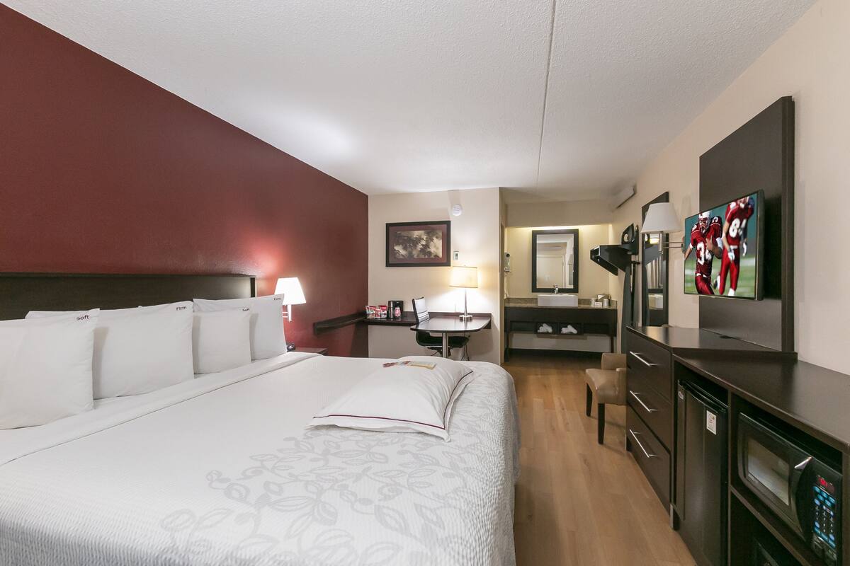 Een hotelkamer met een groot bed, een bureau, een stoel, een televisie en een kitchenette.