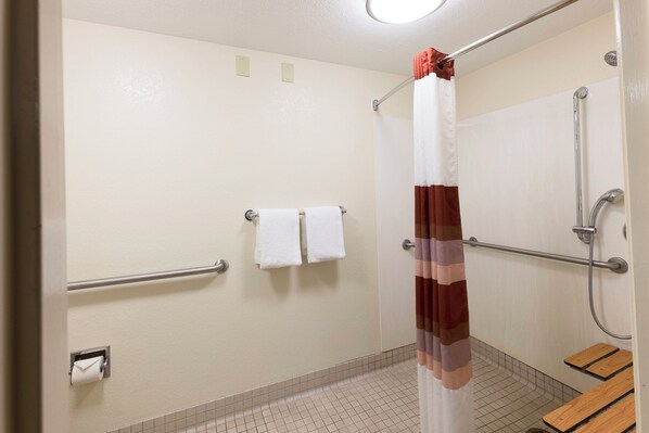 A shower area with a curtain, grab bars, and a towel rack. - Red Roof Inn PLUS+ West Springfield (West Springfield)