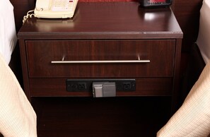 A wooden bedside table with a telephone, a drawer, and a power outlet. - Red Roof Inn PLUS+ West Springfield (West Springfield)