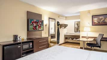 A hotel room with a bed, a desk, a television, a mirror, and a bathroom.