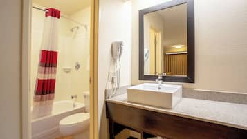 Un baño con bañera, inodoro y lavamanos con espejo.