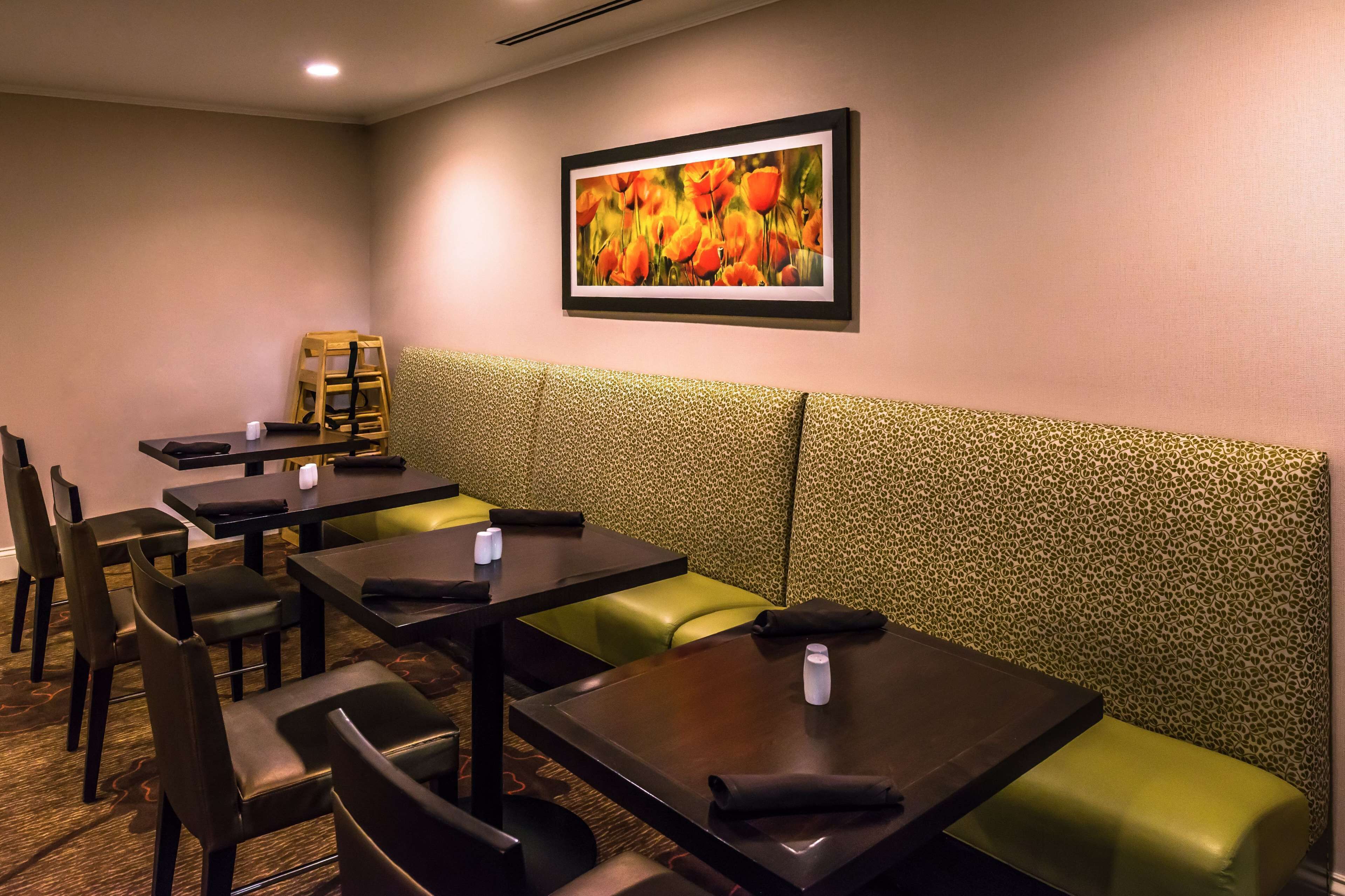 Un restaurante con cabinas y mesas, un cuadro enmarcado en la pared y un diseño decorativo en la pared.
