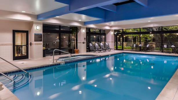 A large indoor swimming pool with clear blue water, surrounded by lounge chairs and a covered seating area.