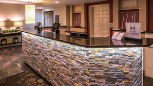 A reception area with a stone wall, a counter with a digital display, and a sign for Hilton Honors.