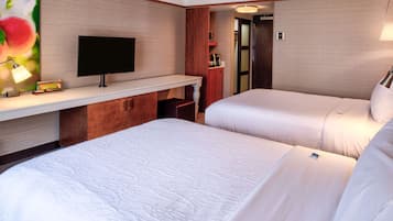 Habitación de hotel con dos camas, televisión, escritorio y espejo.