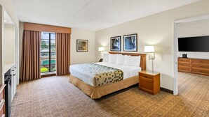 A hotel room with a large bed, a TV, a desk, and a window with curtains. - Econo Lodge Augusta North - Washington Road (Augusta)