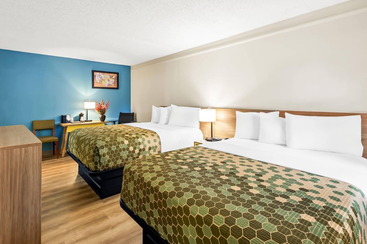 A hotel room with two beds, a desk, and a chair.