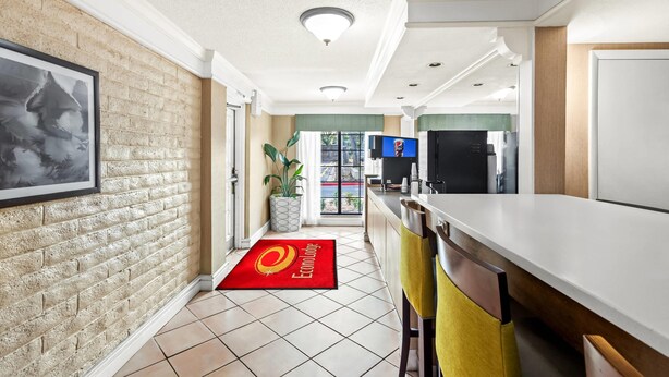 A modern kitchen with a brick wall, a large window, and a red rug with the logo "Econ Lodge". - Econo Lodge Augusta North - Washington Road (Augusta)