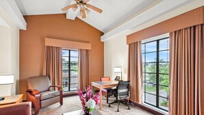 A hotel room with a large window, a dining table, a sofa, a chair, and a vase of flowers. - Econo Lodge Augusta North - Washington Road (Augusta)