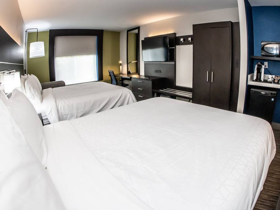 Quarto de hotel com duas camas, uma escrivaninha, televisão, guarda-roupa e minibar.