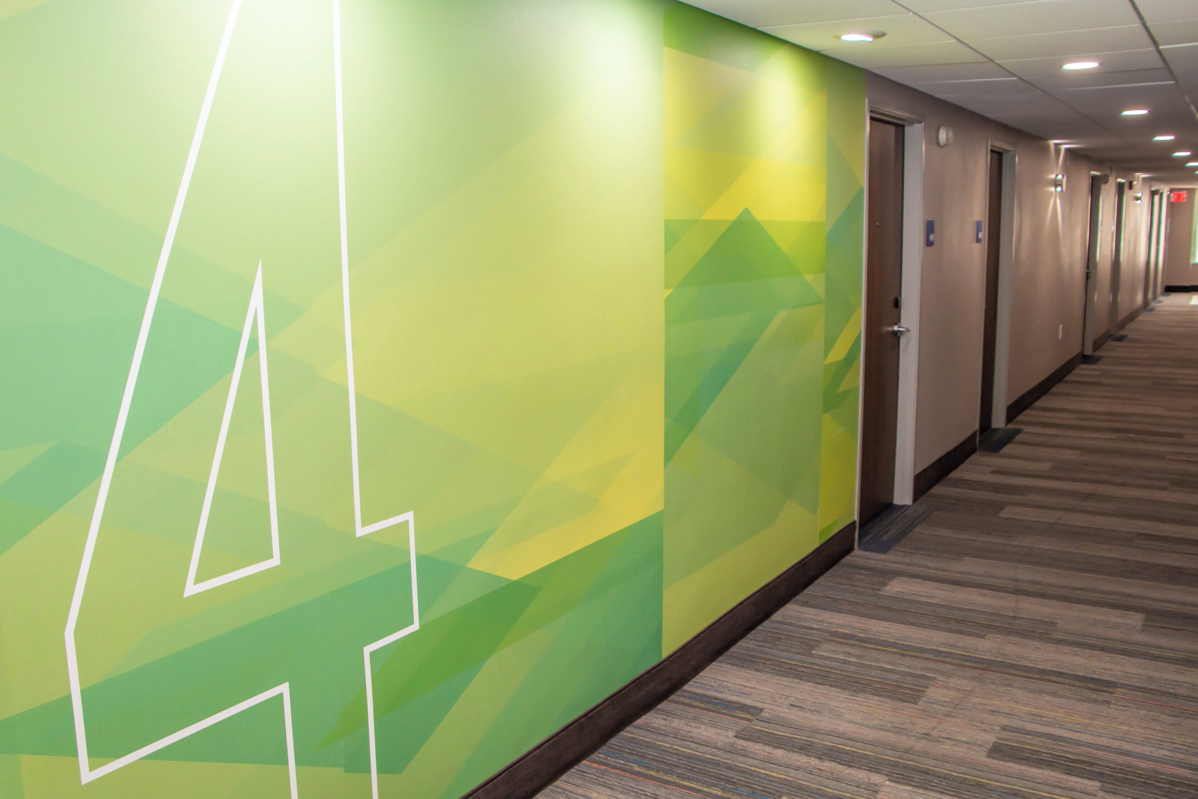 A hallway with a geometric wall design, doors, and carpeted flooring.