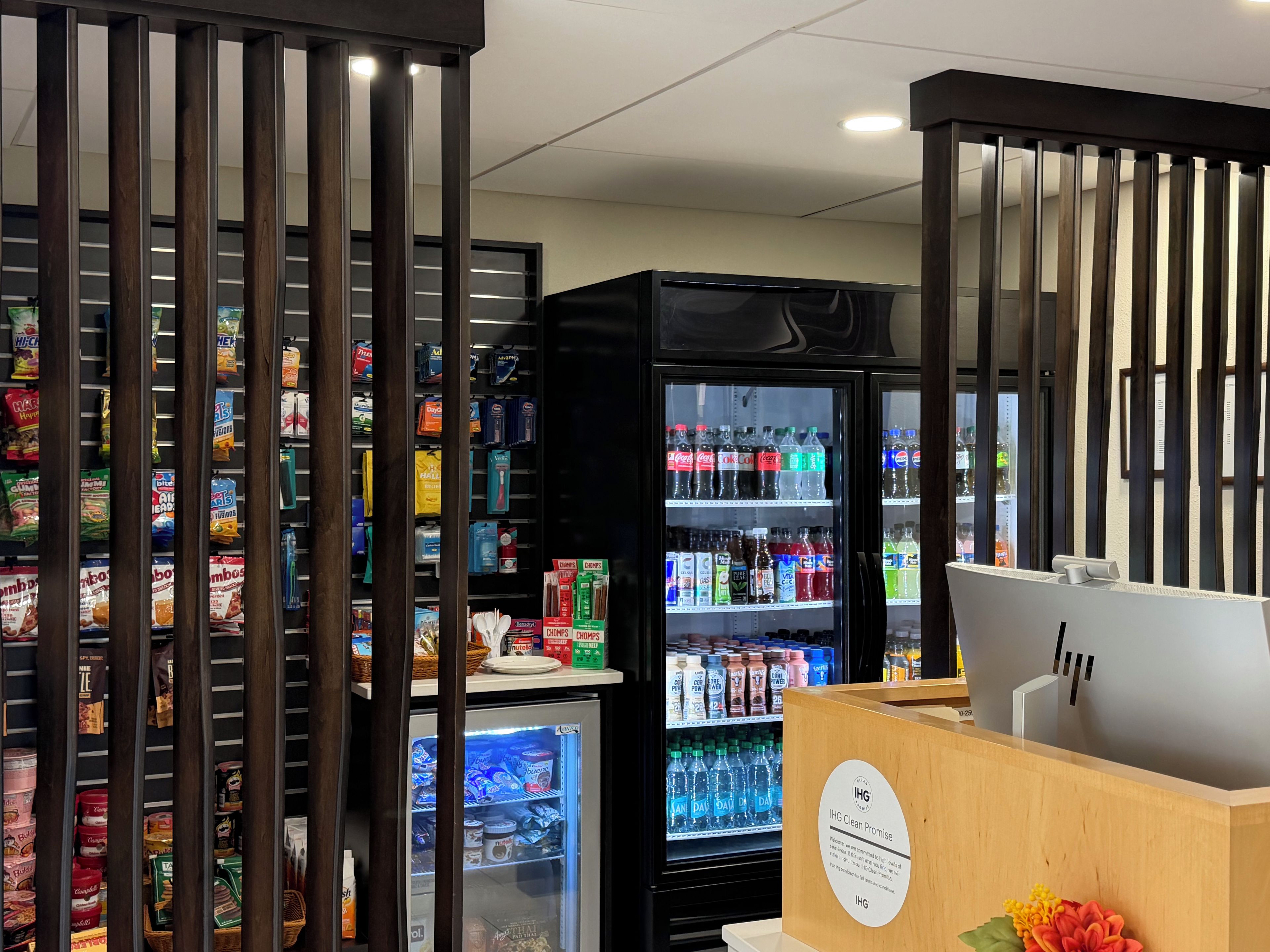 Un espace équipé d’un distributeur automatique de collations et de boissons, d’un réfrigérateur rempli de boissons et d’un comptoir en bois avec une enseigne.