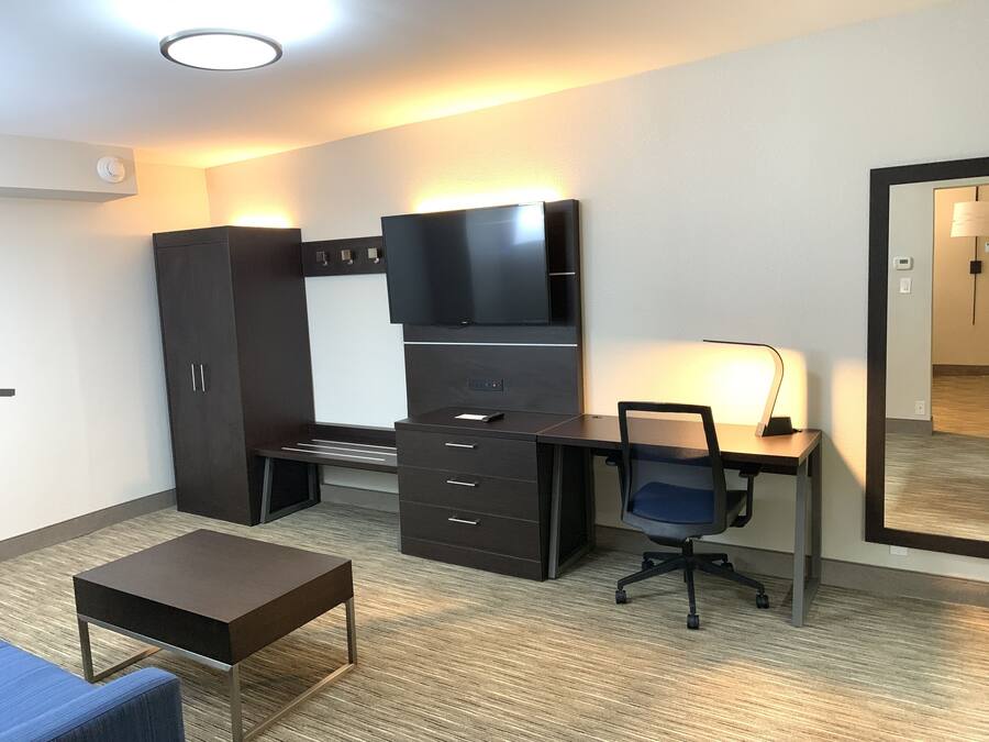 Una habitación de hotel con cama, escritorio, silla, televisor y armario.