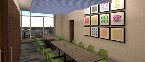 A conference room with a long table, green chairs, and framed artwork on the walls.