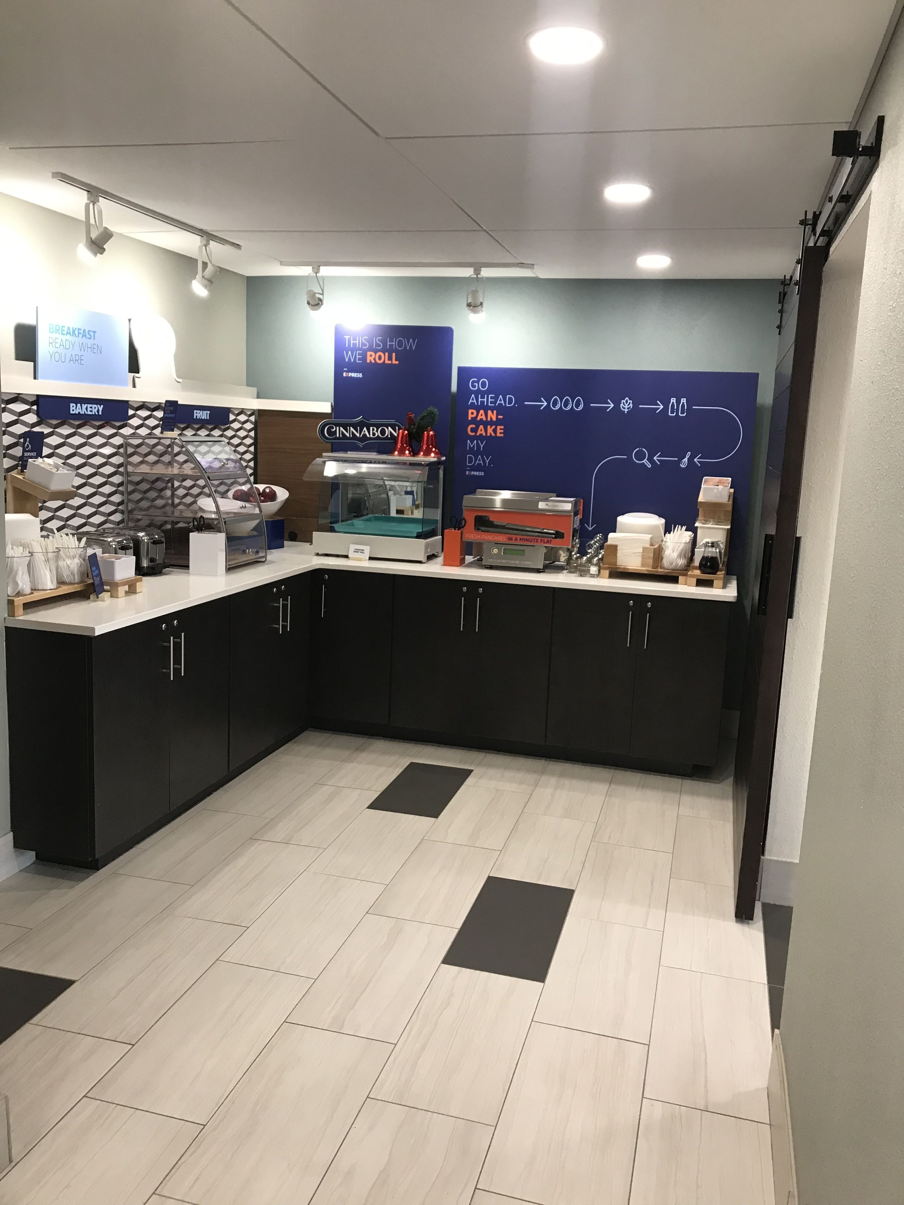 Un'area cucina moderna con un angolo dedicato alla pasticceria, un espositore di frutta e una postazione per il caffè.