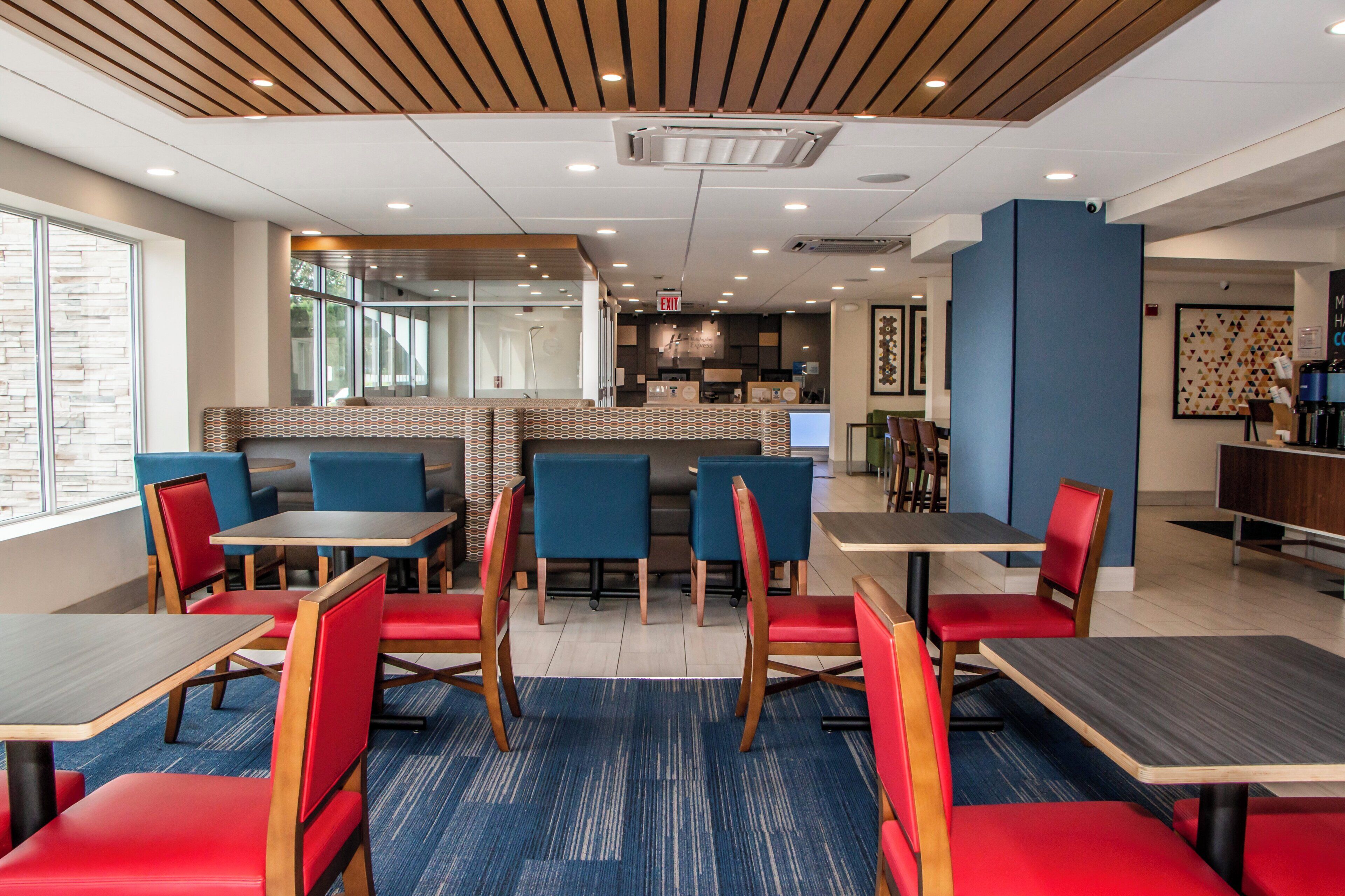 A modern restaurant with booths and tables, a kitchen area, and a blue accent wall.
