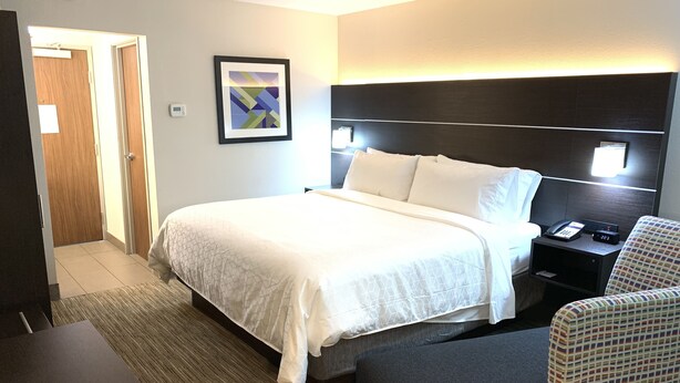 A hotel room with a bed, bedside table, chair, and a painting on the wall. - Holiday Inn Express Allentown North by IHG (Allentown)