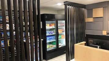 Un interior moderno con una máquina expendedora, un refrigerador lleno de bebidas y una encimera de madera.