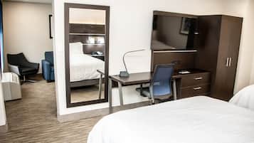 A hotel room with a bed, a desk with a chair, a television, and a wardrobe.