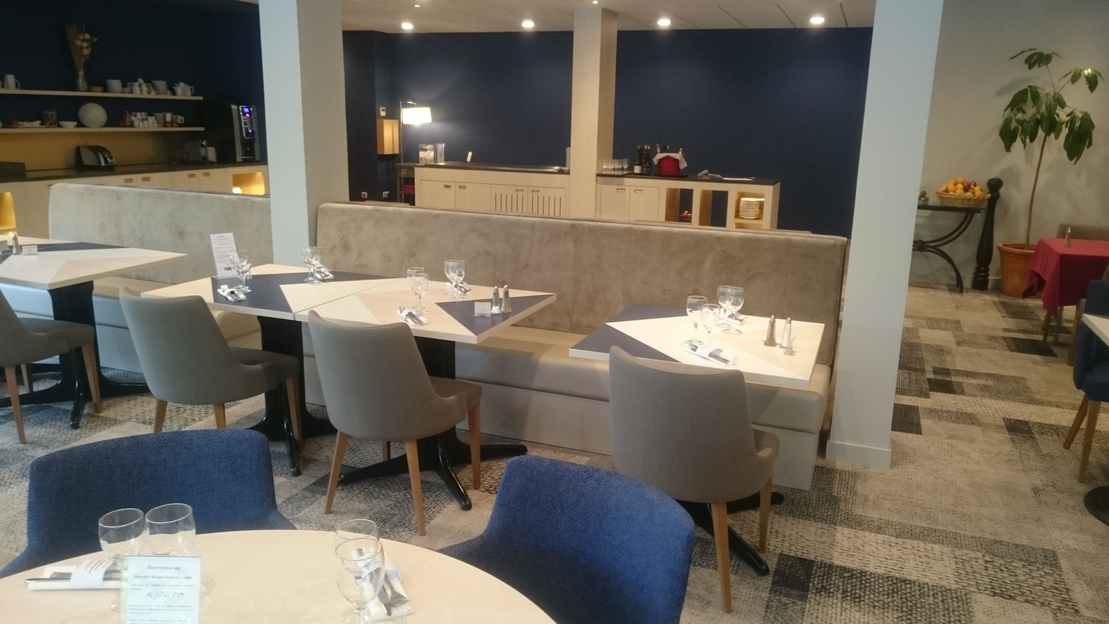 Restaurante com mesas redondas, cadeiras cinzentas e um balcão alto.