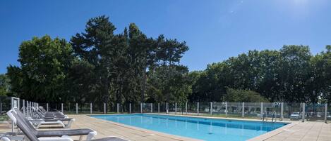 A swimming pool with lounge chairs and a fence.