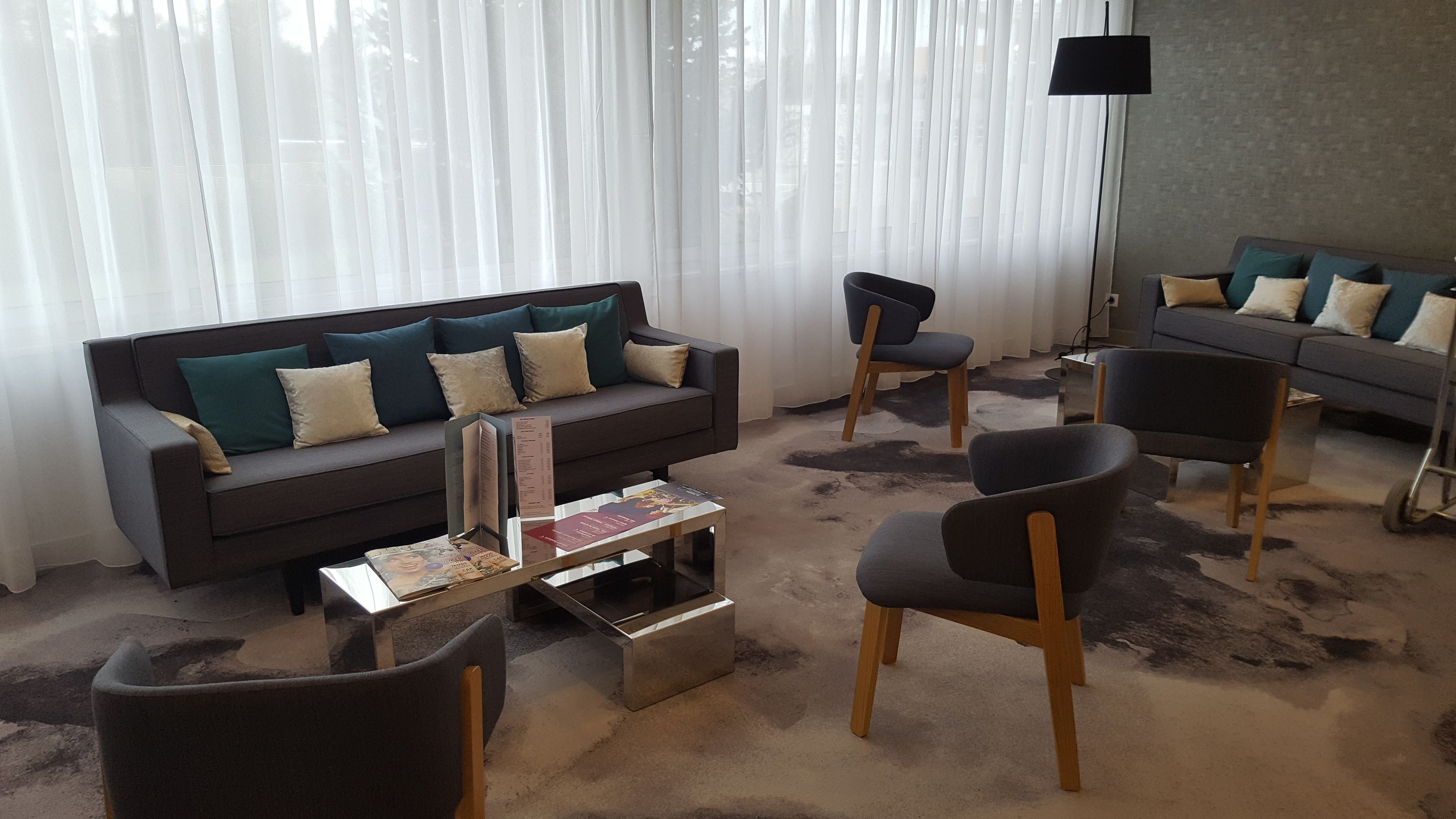 A modern living room with a dark grey sofa, two armchairs, and a coffee table.