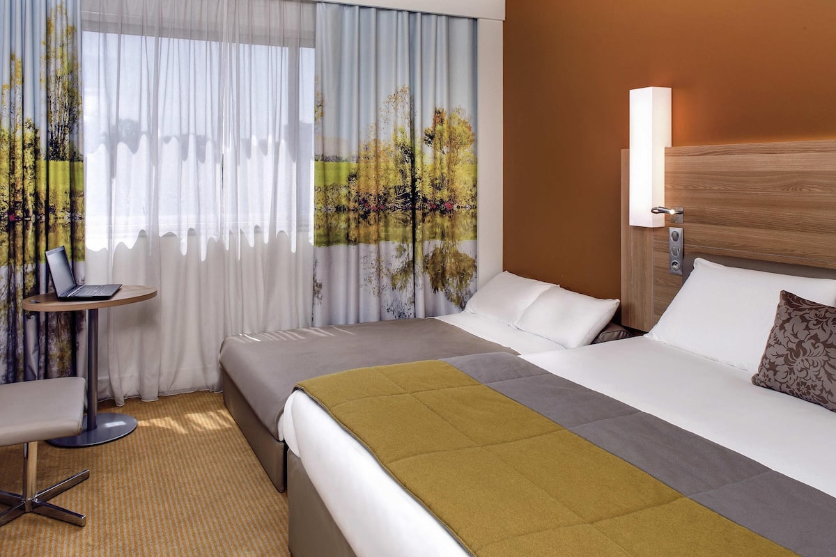 A hotel room with a bed, a desk, and a chair.