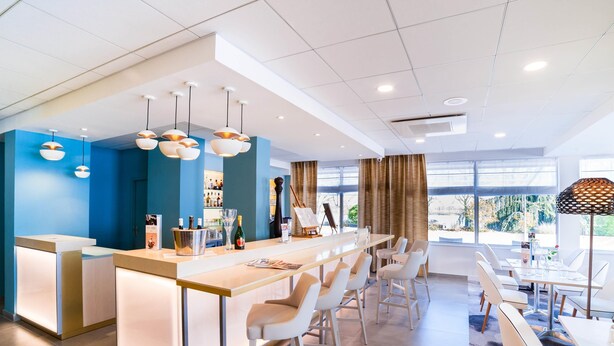 Un hall d’hôtel moderne comprenant un comptoir d’accueil, un bar et un espace détente avec des sièges.
