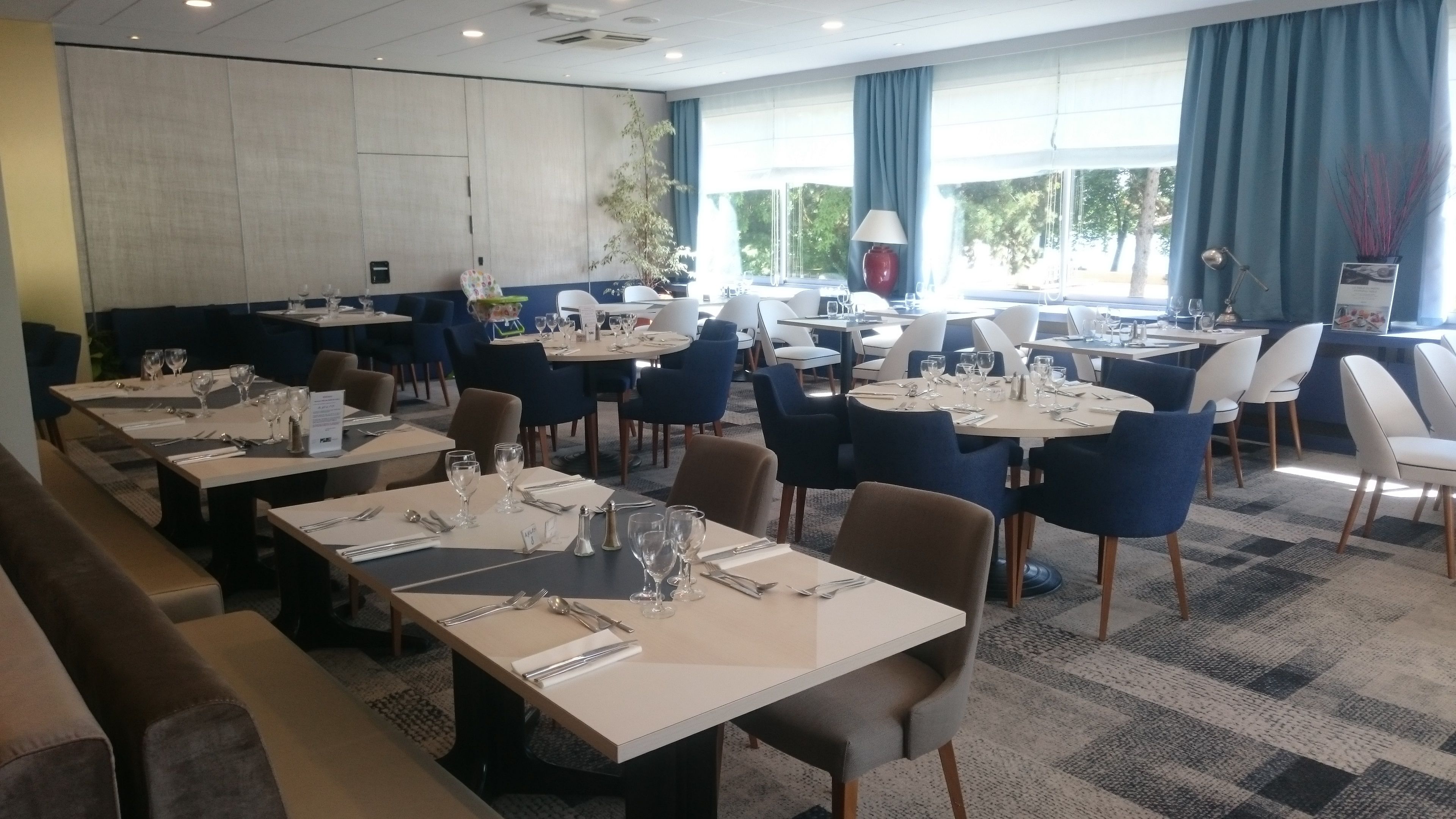 Un'area ristorazione di un hotel con diversi tavoli e sedie, disposti in un ambiente spazioso.