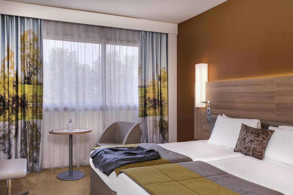Een hotelkamer met een bed, een stoel, een tafeltje en een lamp.