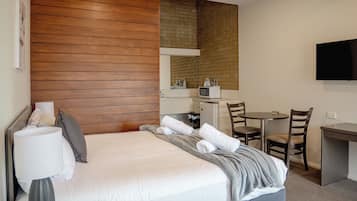 Une chambre d’hôtel équipée d’un lit, d’un bureau, d’un four à micro-ondes et d’une télévision.