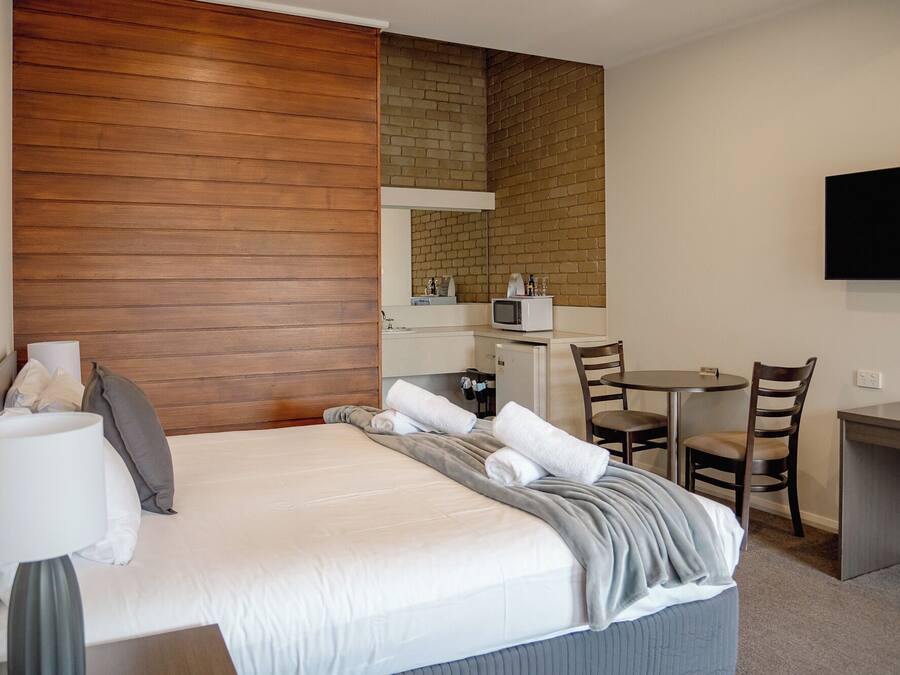 A hotel room with a bed, a desk, a microwave, and a TV.