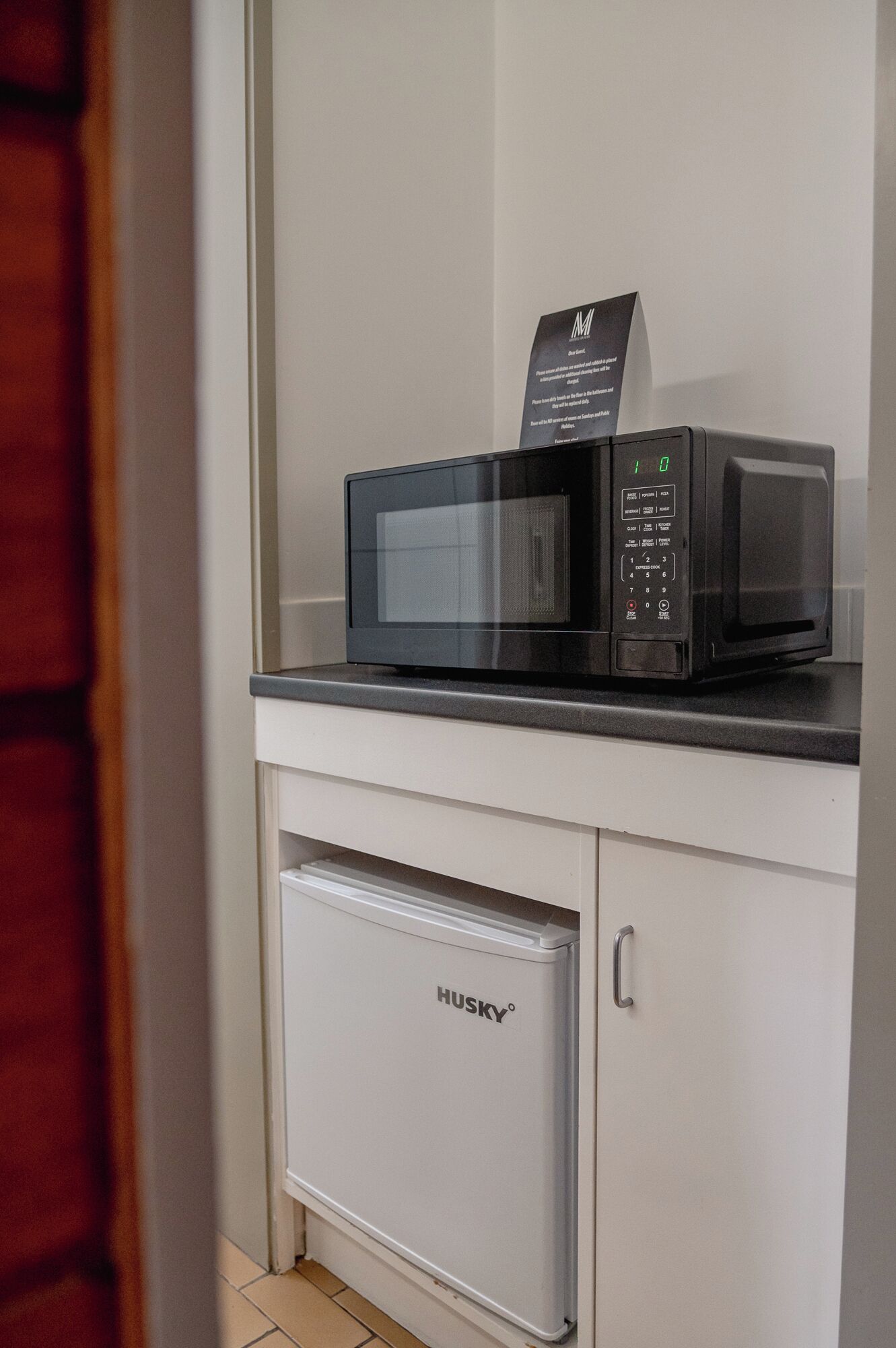 A compact kitchen area with a microwave and a small refrigerator.