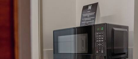 A compact kitchen area with a microwave and a small refrigerator.
