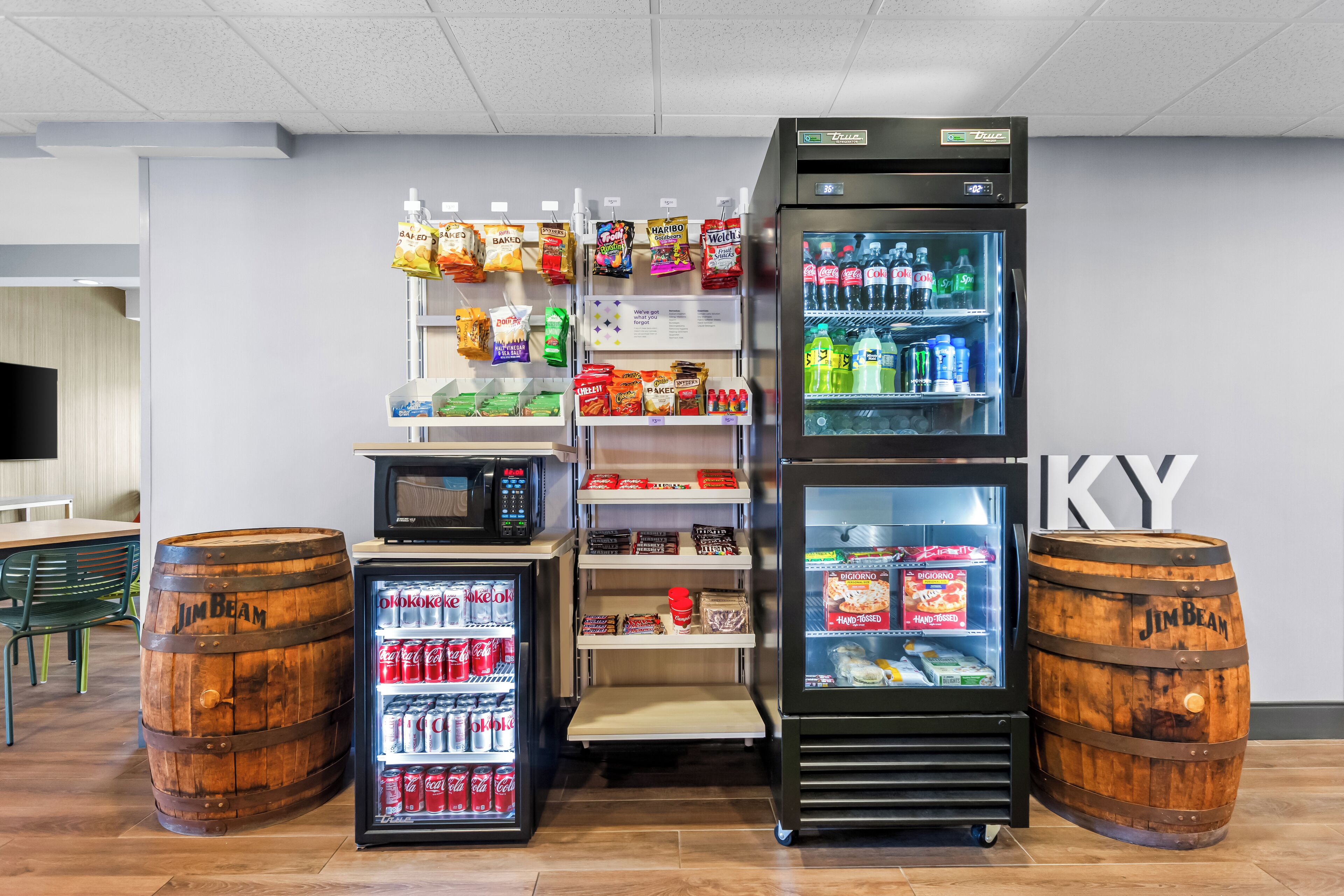 Un distributeur automatique rempli d’en-cas et de boissons, un four à micro-ondes et un réfrigérateur contenant des boissons.