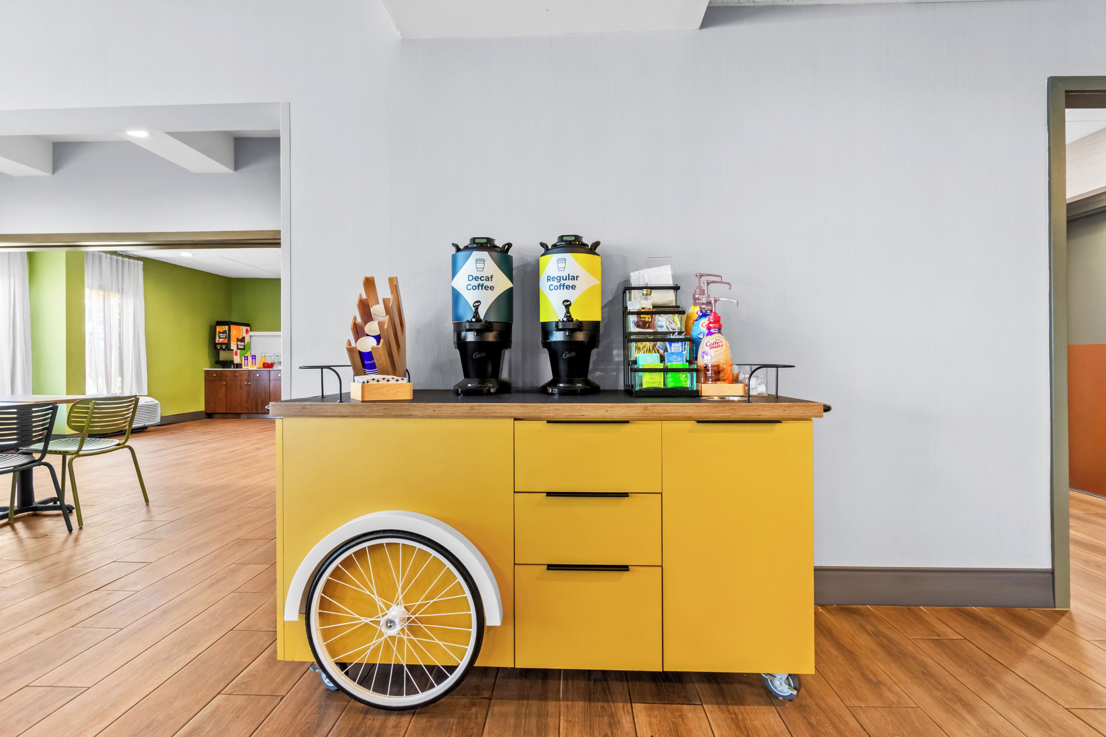 A yellow counter with coffee machines and a wheelchair-accessible design.