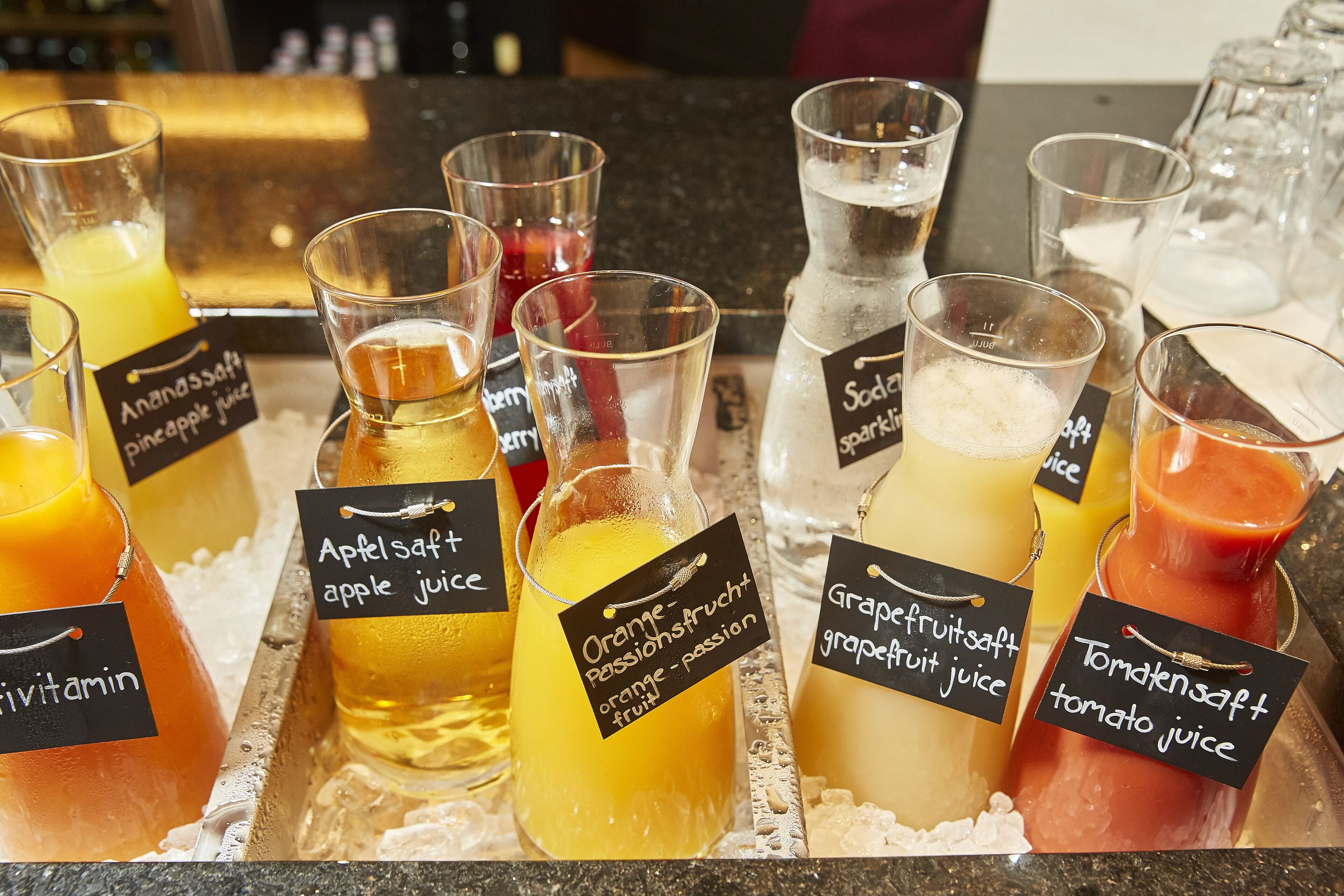 A variety of juices in bottles and glasses, each labeled with their type.
