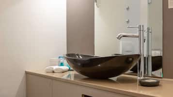 A modern bathroom with a sleek black vessel sink, a chrome faucet, and a large mirror above the sink.